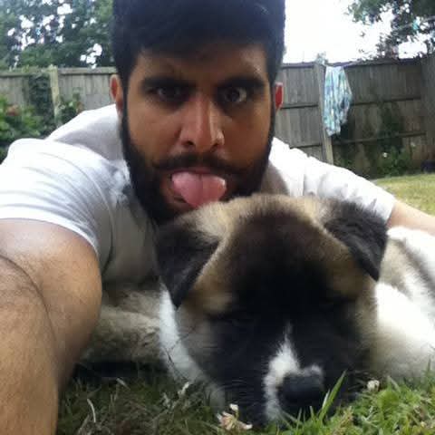 Karan Singh Bains lying beside a puppy in a garden